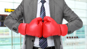 Male wearing a suit and boxing gloves in a competitive stance.